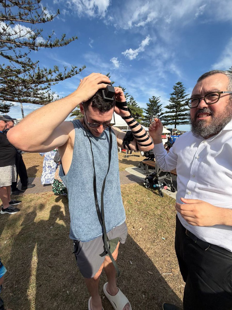 Hours before he was murdered: Rabbi Eli Schlanger Z"L HYD, helps a young Jewish man put on tefillin this morning 💔