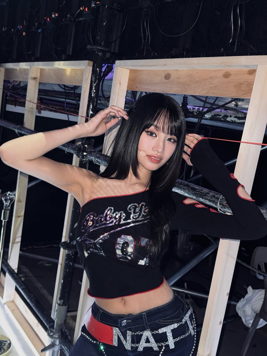 Backstage glow hitting just right
Serving full Y2K revival in this asymmetric one-shoulder crop top — black base with red piping, sparkling rhinestone 'Baby Phat 01' graphic shining under the stage lights, and that single long sleeve with cut-out details for extra edge