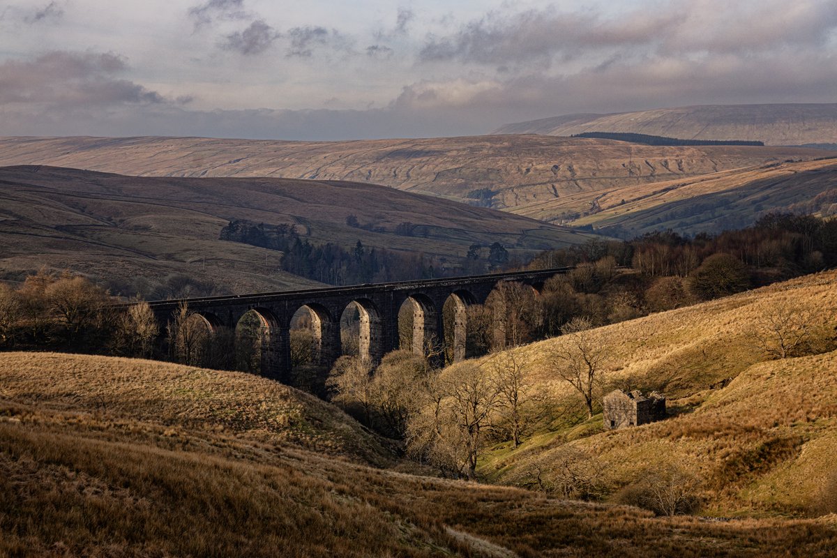 The arches of Dent Head Viaduct catch the late afternoon sun on a chilly winter’s day, with the surrounding hills standing still.