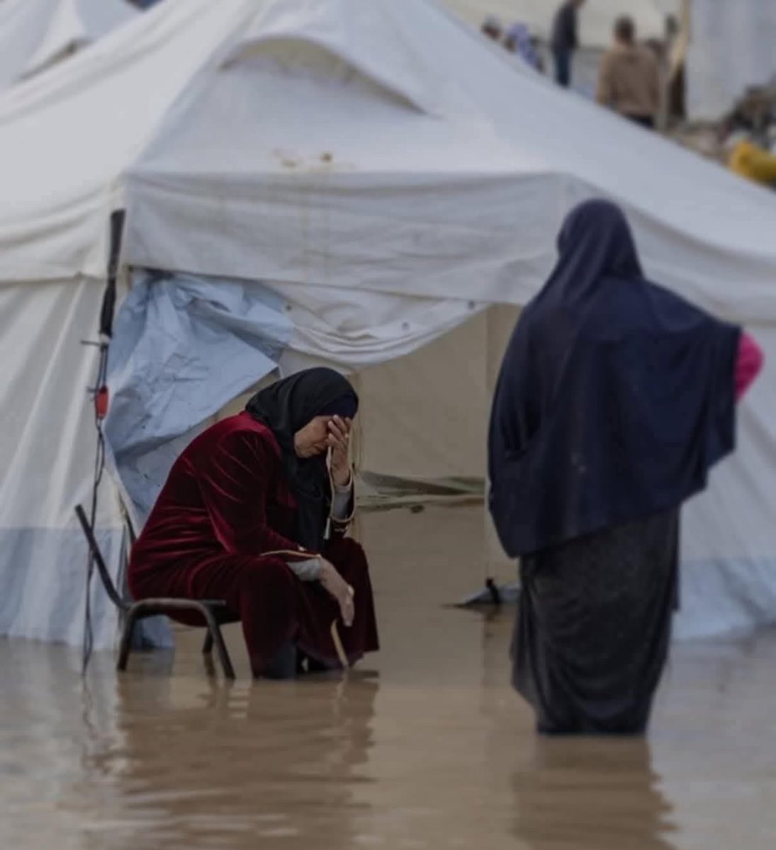 This isn't a picture…it's a story of pain.

A Palestinian woman, her heart heavy with sorrow, her tent flooded.

Here, the suffering is compounded, not by the rain…
