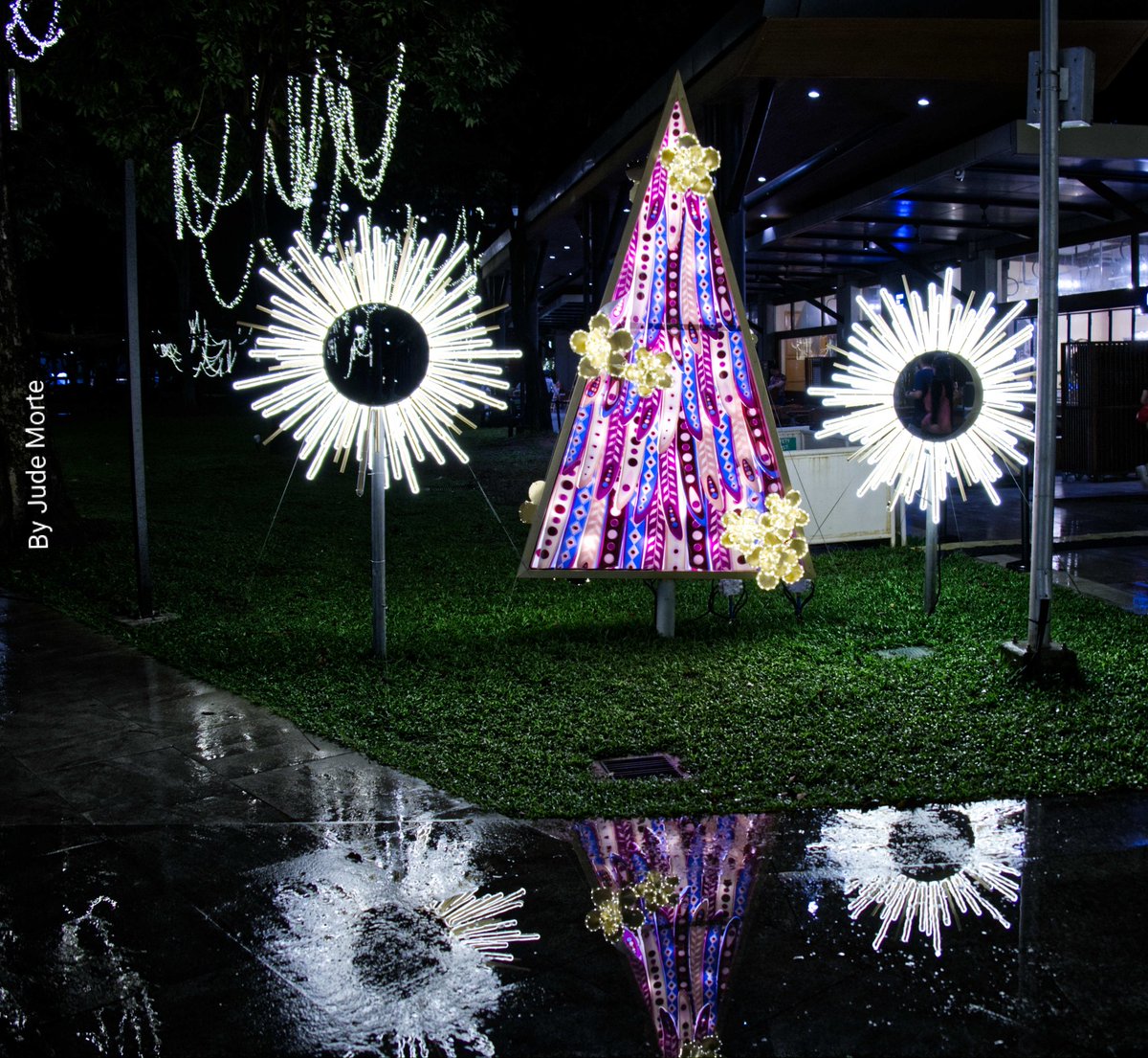 MorteJude's tweet photo. @JohnGetchel John, here's a #nightshot of some #ChristmasDecorations from a park in Makati City, Philippines 🇵🇭 
Taken 12/15/25, after a constant drizzle 🌧️

#Reflection #fujifilmxm5 #parol #ChristmasTree https://t.co/Kwlu4JG8xh
