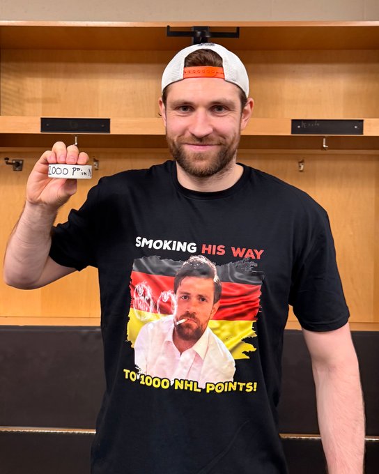 Leon Draisaitl holding his 1000 point puck.
