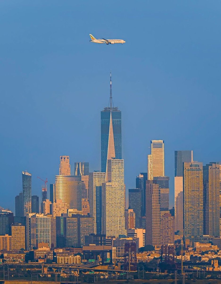 ajosephstyl3's tweet image. Iconic twilight shot over Midtown Manhattan: One Penn 1’s pointed spire centers the glowing skyline An Ethiopian Airlines jet, gear down, flies perfectly aligned overhead against a deep blue sky. A stunning symbol of NYC’s energy and global aviation. #NYCSkyline 
@flyethiopian