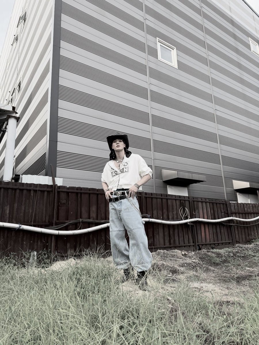 Twildight's tweet image. Rockin’ a proper fit, cowboy hat tipped low, layered chains on show, cropped hoodie and baggy denim. Posted up by that rough wall like it’s a runway, lookin’ effortlessly cool?