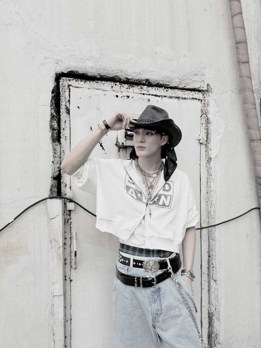 Twildight's tweet image. Rockin’ a proper fit, cowboy hat tipped low, layered chains on show, cropped hoodie and baggy denim. Posted up by that rough wall like it’s a runway, lookin’ effortlessly cool?