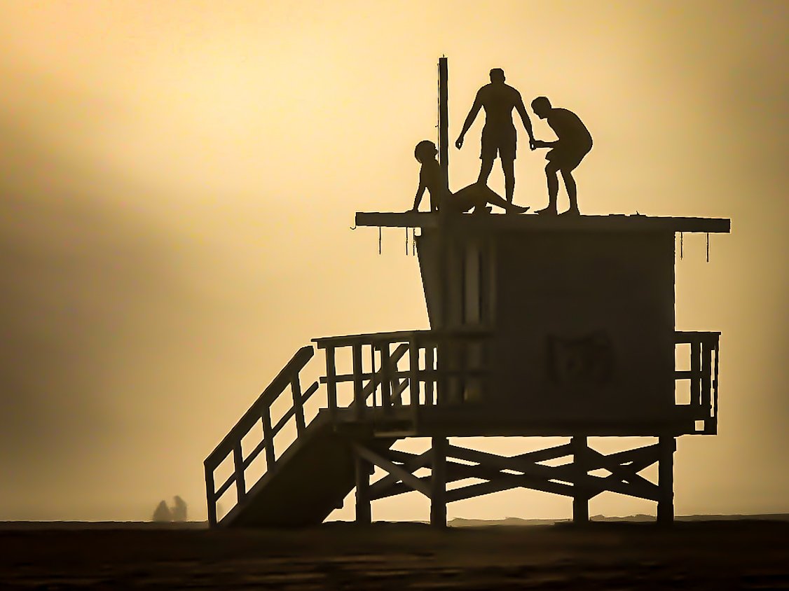 smcloseup's tweet photo. Silhouettes gather atop a Santa Monica lifeguard tower as fog softens the shoreline—figures suspended in the haze, with the beach below moving quietly through the day.

📷 @WCoast_ https://t.co/oYBbIjJ6G3