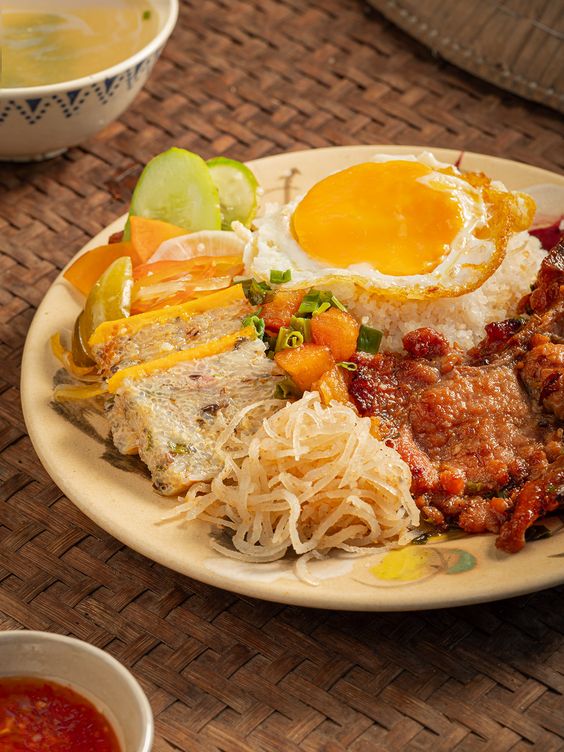 phai97152's tweet image. Indulge in Rạch Giá’s famous broken rice with succulent grilled ribs, savory pork skin, and egg meatloaf. Paired with tangy-sweet-spicy fish sauce, this dish is truly unforgettable🥰🌿🌺🪻