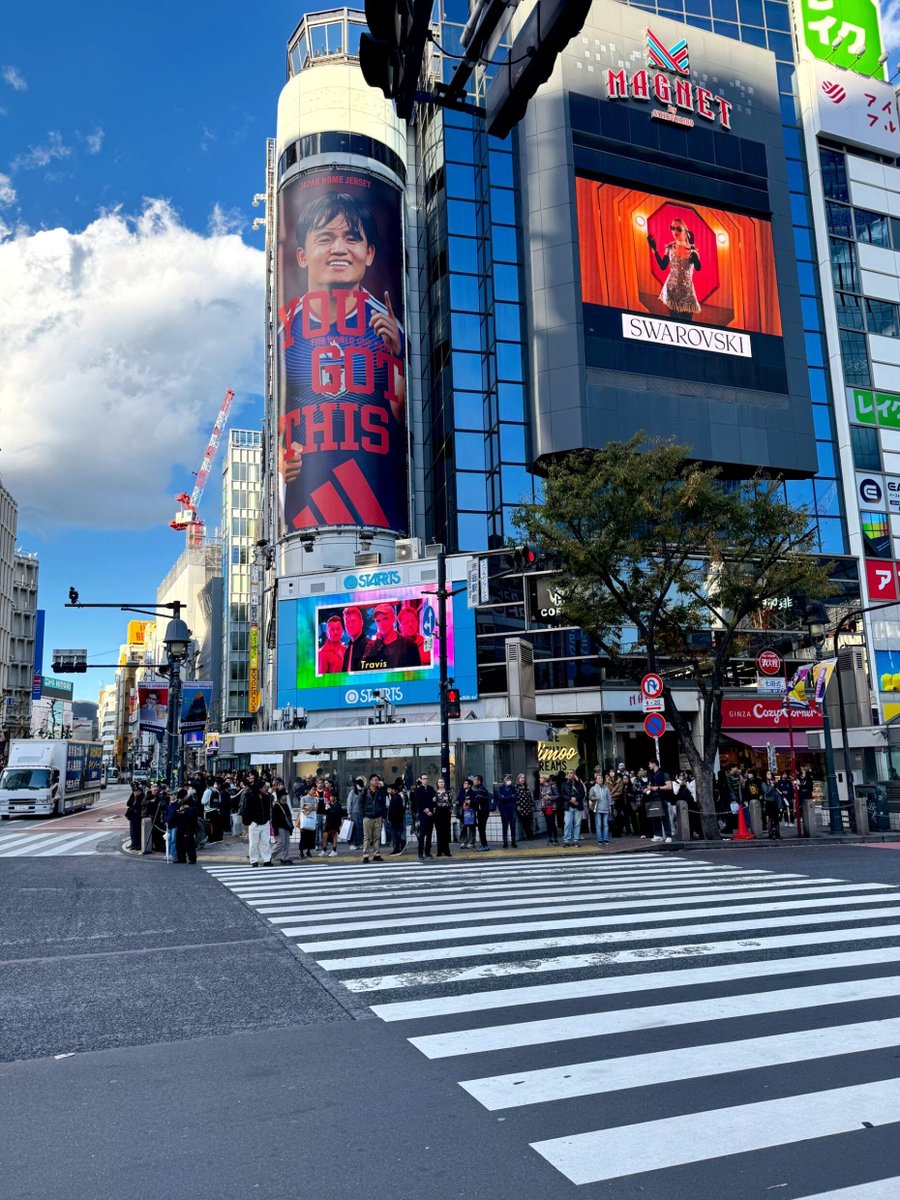 渋谷のスクランブル交差点を渡ると、街全体が色鮮やかな広告や映像で溢れていて、まるで映画のワンシーンのようです。大きなビルの壁に映し出される選手の顔や、華やかなショーの映像が、都会のエネルギーを感じさせます。