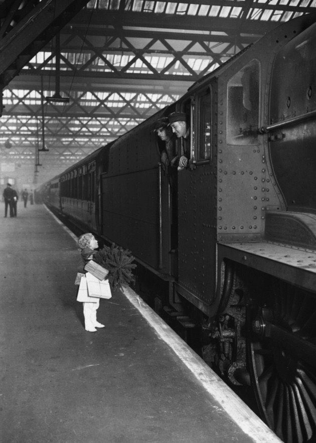 HistoryGirlBW's tweet image. A little girl, clutching her Christmas parcels and a small tree, chats to the train drivers at Euston Railway Station in London. A lovely photo taken on this day, 22nd December 1936.