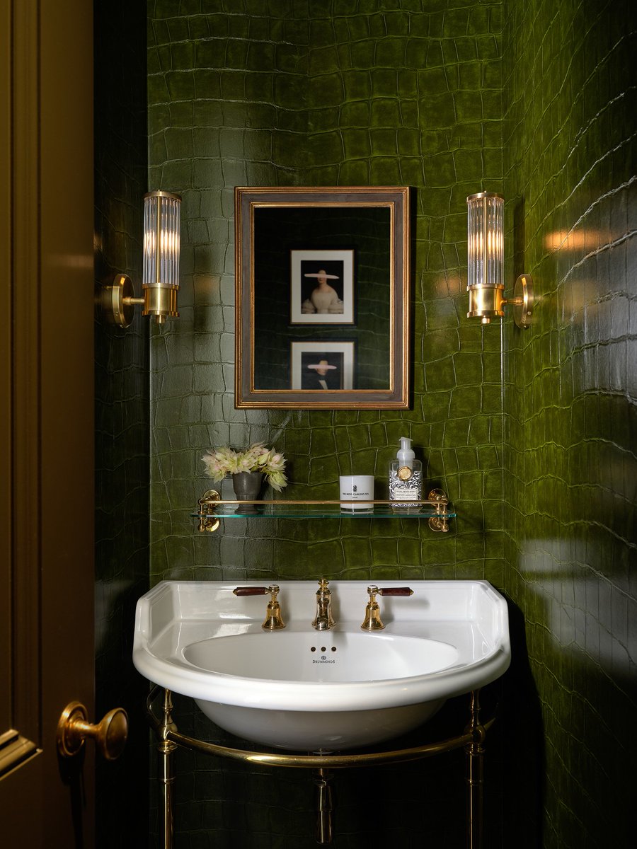 Tucked within a Rittenhouse Square townhouse, this jewel-box cloakroom balances atmosphere and restraint. Deep green faux-crocodile wallpaper glows beneath fluted glass sconces. The Kinloch Vanity with china basin and unlacquered brass taps brings classical clarity.