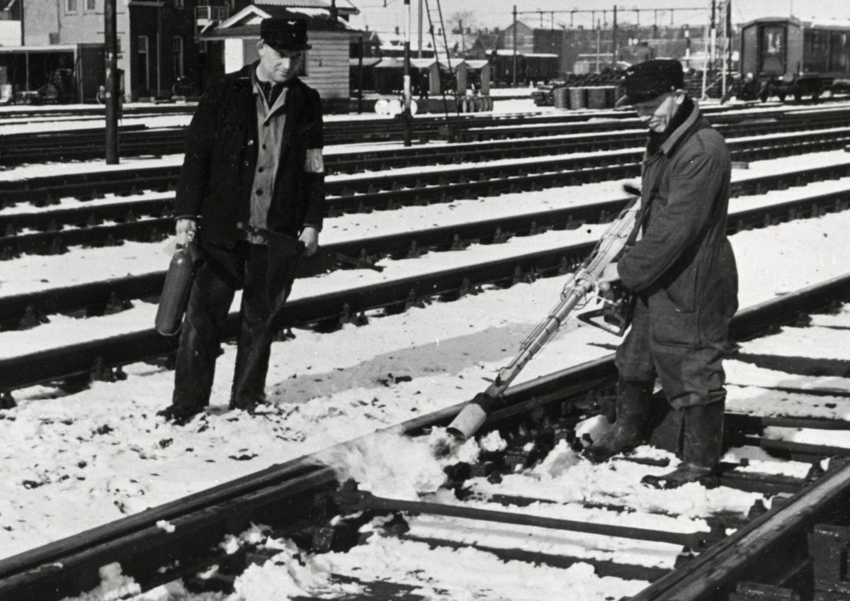 Twee wegwerkers van NS ontdooien een vastgevroren wissel, 1958. De kennis van dit oude ambacht is helaas verloren gegaan.