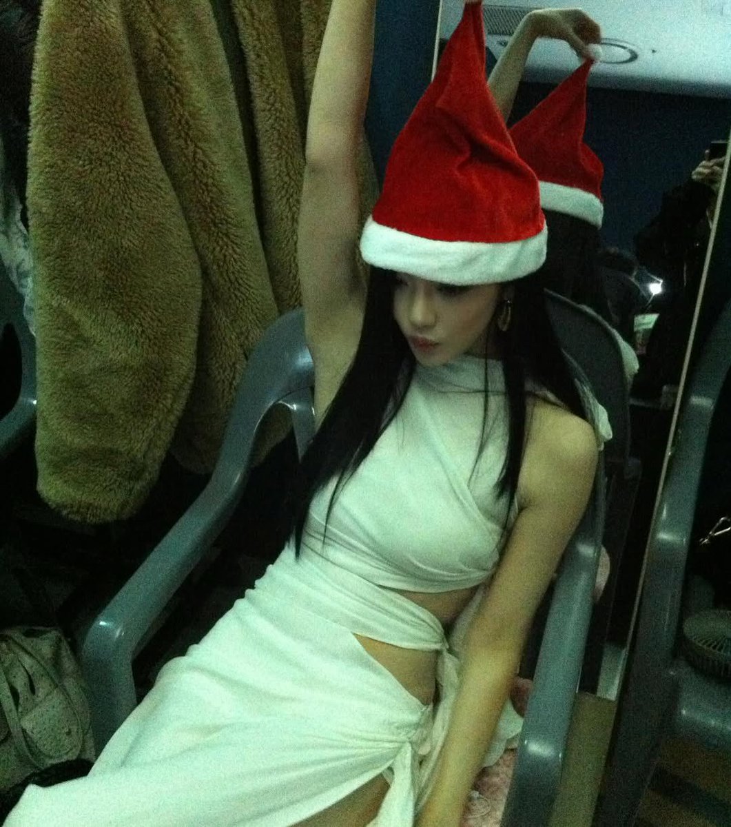 White dress, red hat, holiday chill~ 🌙✨  sometimes all you need is just a santa hat and a cozy chair to feel the holiday spirit~ merry christmas from me to you, let’s make this season unforgettable! 🎄💖