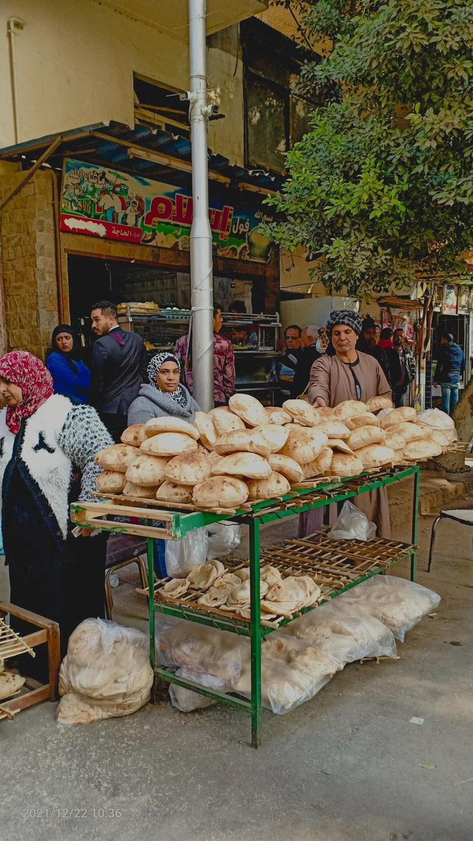 اسمي "عم أحمد". عندي مخبز صغير في حي شعبي بقاله 30 سنة. ريحة العيش السخن هي كل حياتي. شفت أجيال بتكبر قدام الفرن بتاعي.

أنا مش بس ببيع عيش.. أنا بقرأ الوشوش.

كنت بلاحظ راجل عجوز، لبسه مهندم جداً بس قديم، بيجي كل يوم الساعة 2 الضهر. يقف بعيد شوية عن الزحمة، يبص على العيش