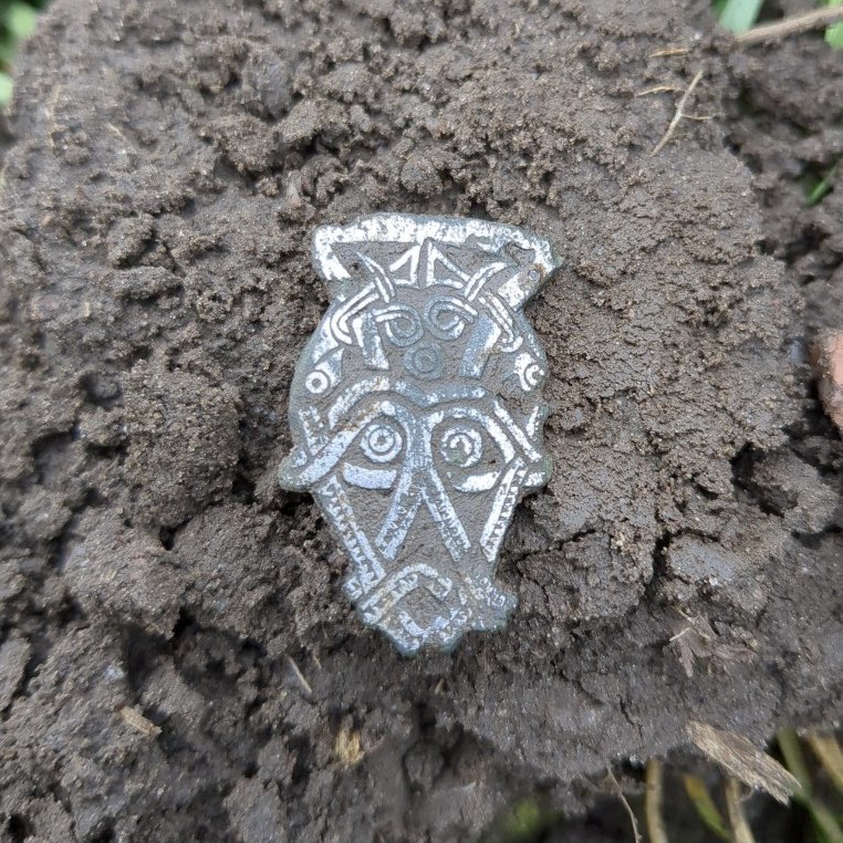 Sagnamadr's tweet image. Beautiful Iron Age zoomorphic mask recently found in Nordfyn, Denmark. The animals look like they could have long tongues or tusks; perhaps Odin with Freki and Geri, or Freyr with two boars. Like many Roman Cornuti emblems, the animals have an orb between them; Odin’s eye? ᚨ