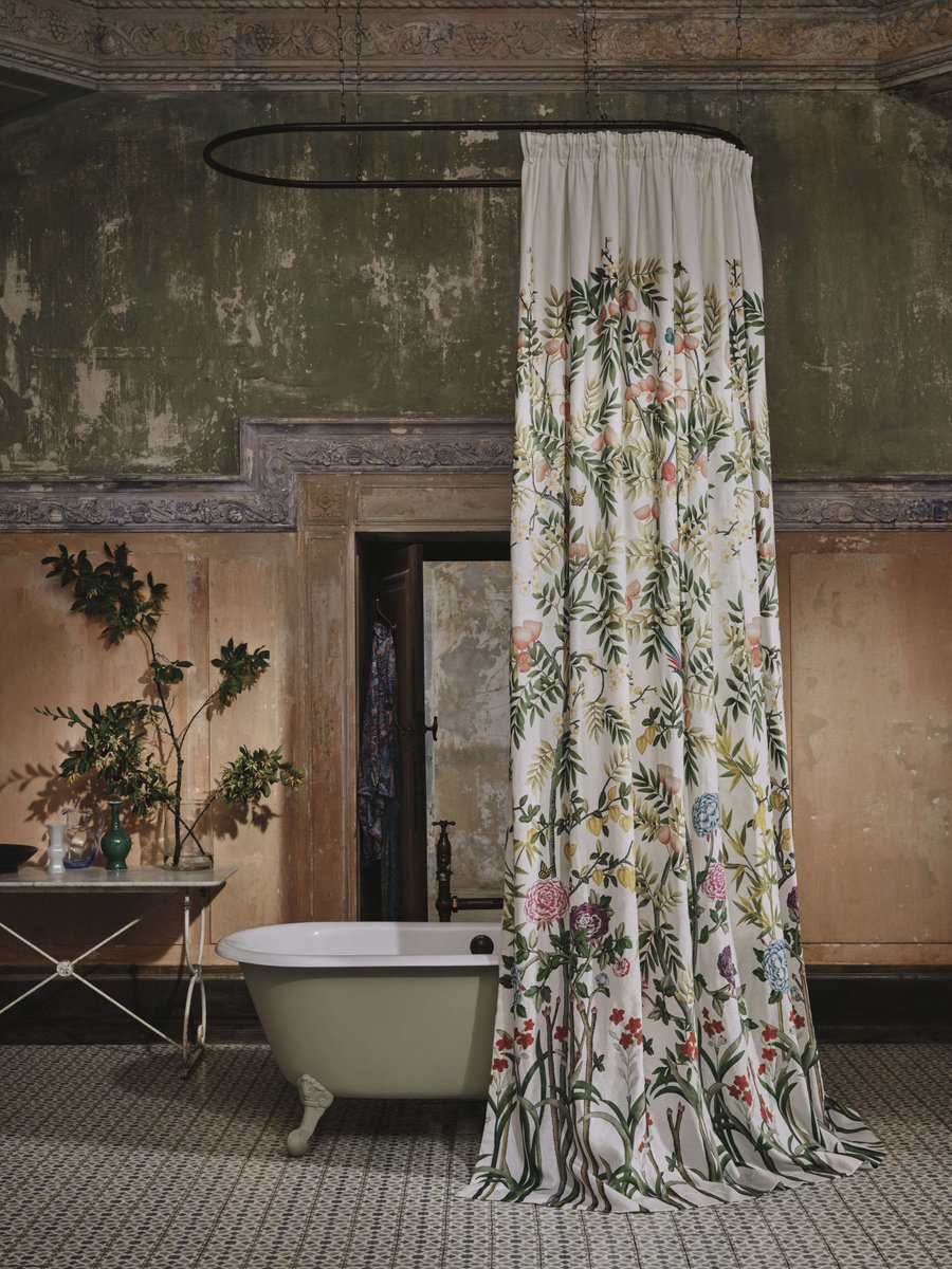 Soft light and layered surfaces shape this atmospheric bathroom, where the Ashburn bath sits against timeworn plaster and mouldings. Its lichen green exterior echoes the muted palette, while Liberty’s Silk Tree linen curtain brings pattern and a gentle sense of the outdoors.