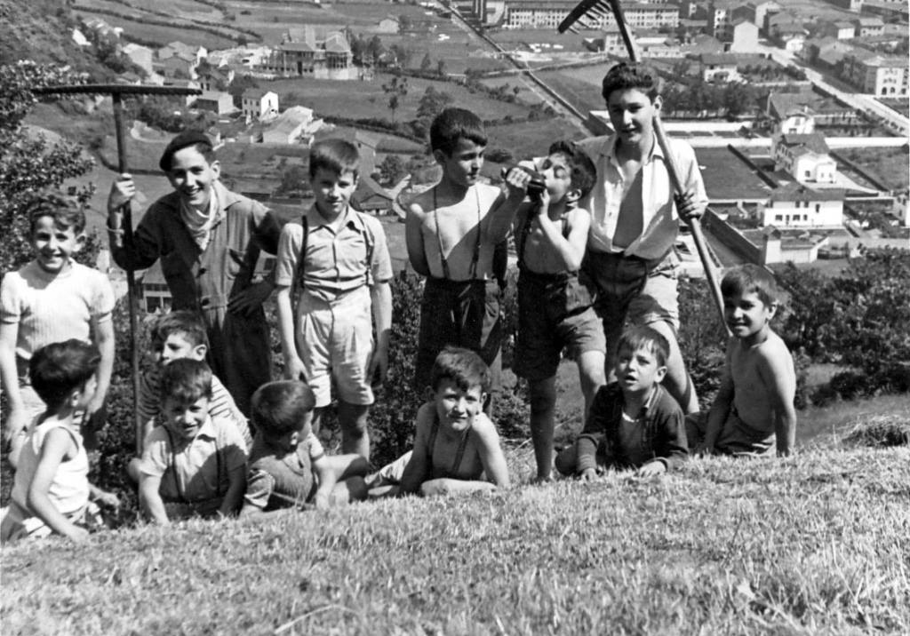 LaFelgueraWeb's tweet image. Una imagen que parece de película: unos chavales posan en un prau. Al fondo se ve el Patronato de San José en construcción, los chalés del Nitrógeno, los barrios de Candín y Sandín, y el río Candín aún al descubierto antes de su abovedamiento #Asturias #LaFelguera #Langreo