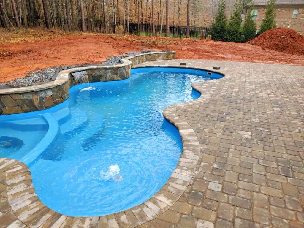 PoolscapesCLT's tweet image. The Desert Springs #fiberglasspool model. The pool features a built-in spa and tanning ledge. For this project, we installed pavers #pooldeck and coping and a sheer descent waterfall against the retaining wall. #pool