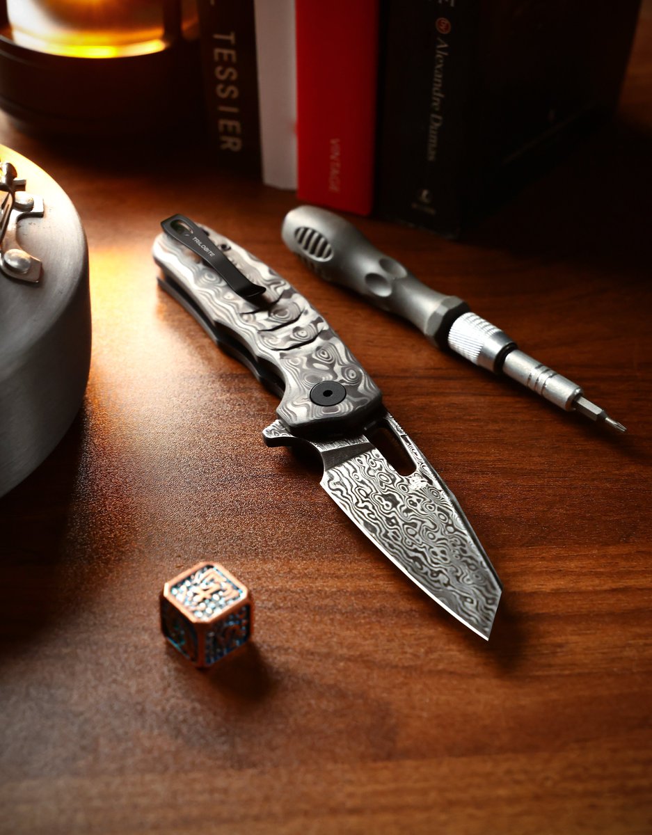 FishPetrified's tweet photo. A new fossil emerges from the dark. 🖤
​Introducing the Trilobite Full-Black Edition. We’ve merged the raw, organic texture of stone-pattern carbon fiber with the hypnotic ripples of a black Damascus blade.
​This isn't just assembly; it’s evolution. Every single scale and blade undergoes exhaustive rounds of hand-finishing to reveal a pattern that is yours and yours alone. No two pieces are ever the same.
​The ultimate fusion of prehistoric soul and modern precision.

Available now
🔗 Link in bio