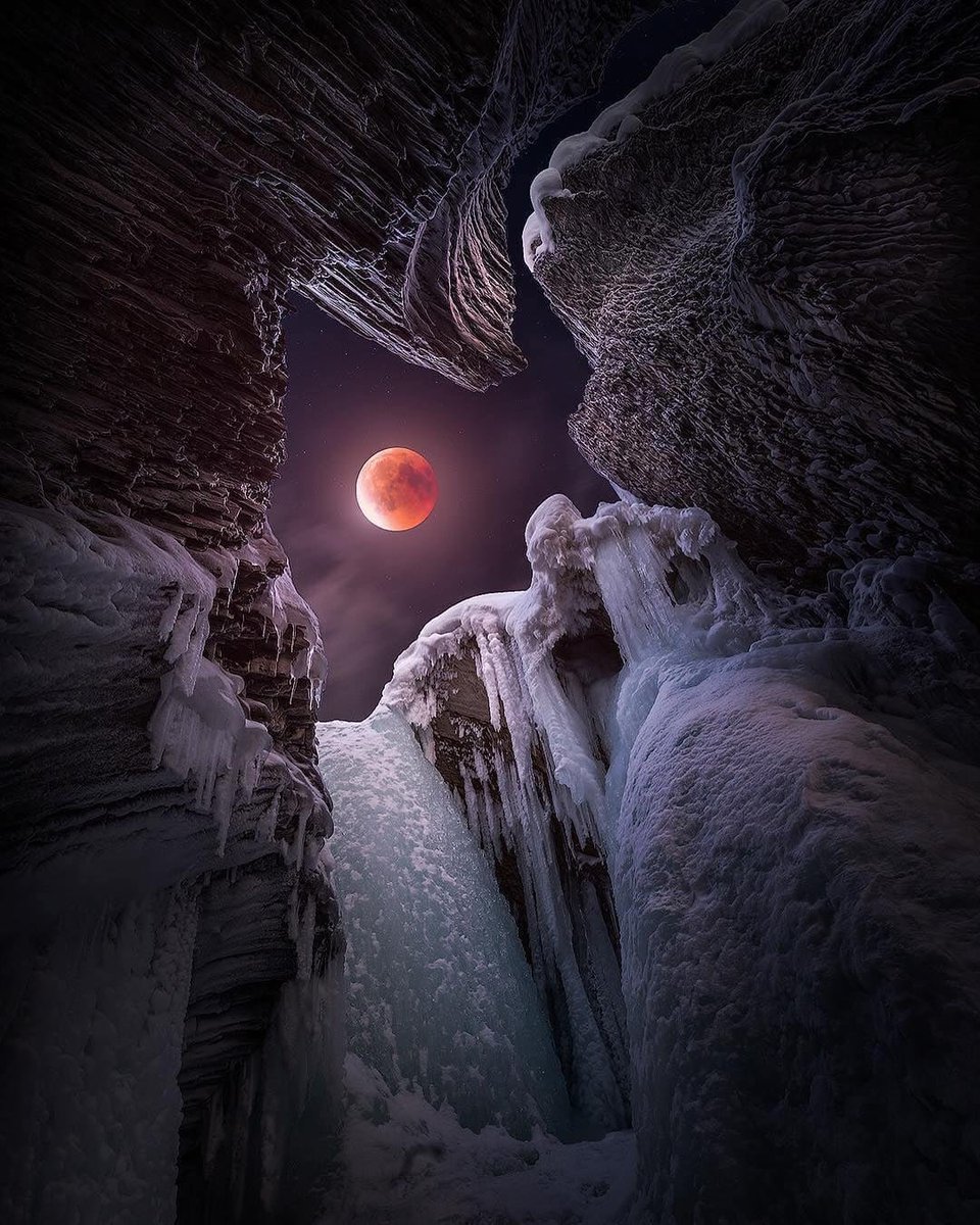 A vibrant red blood moon glows brightly amidst swirling red and purple  clouds in a star-filled night sky. on Craiyon, image size:960x1200