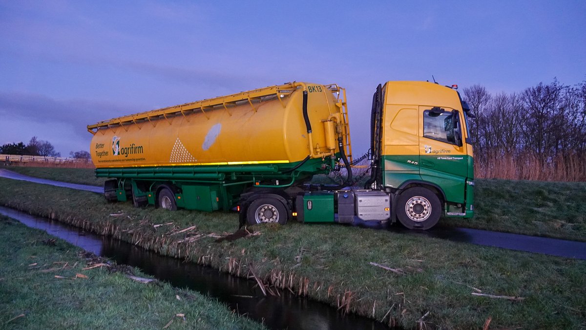 Vrachtwagen dreigt om te vallen op spekgladde dijk