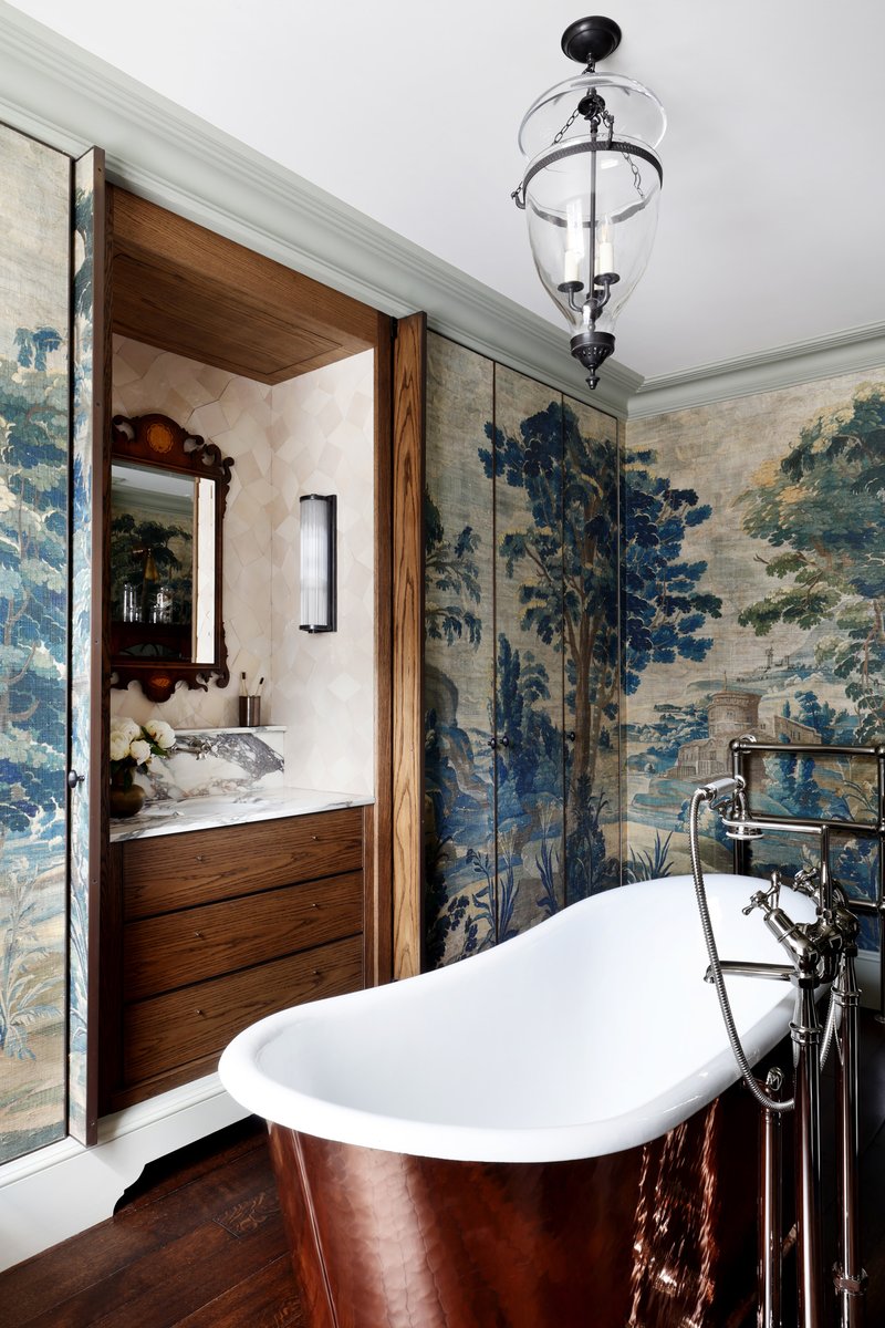Drummonds_uk's tweet photo. Washed in pattern and tone, this bathroom balances function and atmosphere. A concealed vanity sits behind pocket doors, keeping the space uncluttered, while a hammered copper Wye bath becomes a sculptural focal point against Watts 1874 wallpaper in a grand London townhouse. https://t.co/FpexZpr1E9