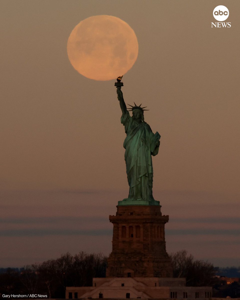 ABC's tweet image. The full Wolf Moon supermoon sets behind the Statue of Liberty as the sun rises on Saturday, in New York City. abcnews.link/6uhooY2