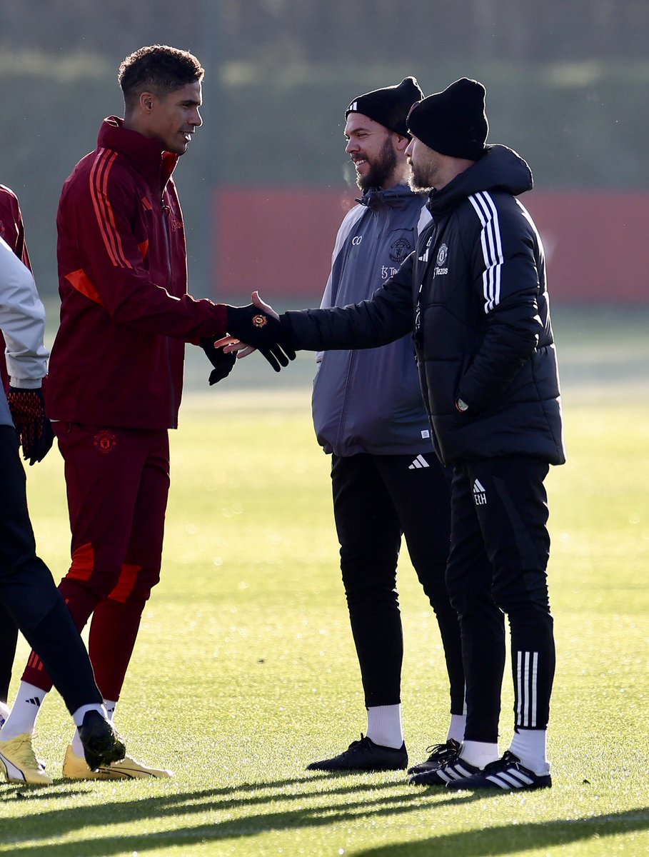 Raphael Varane and Erik ten Hag shake hands ahead of training at Carrington.