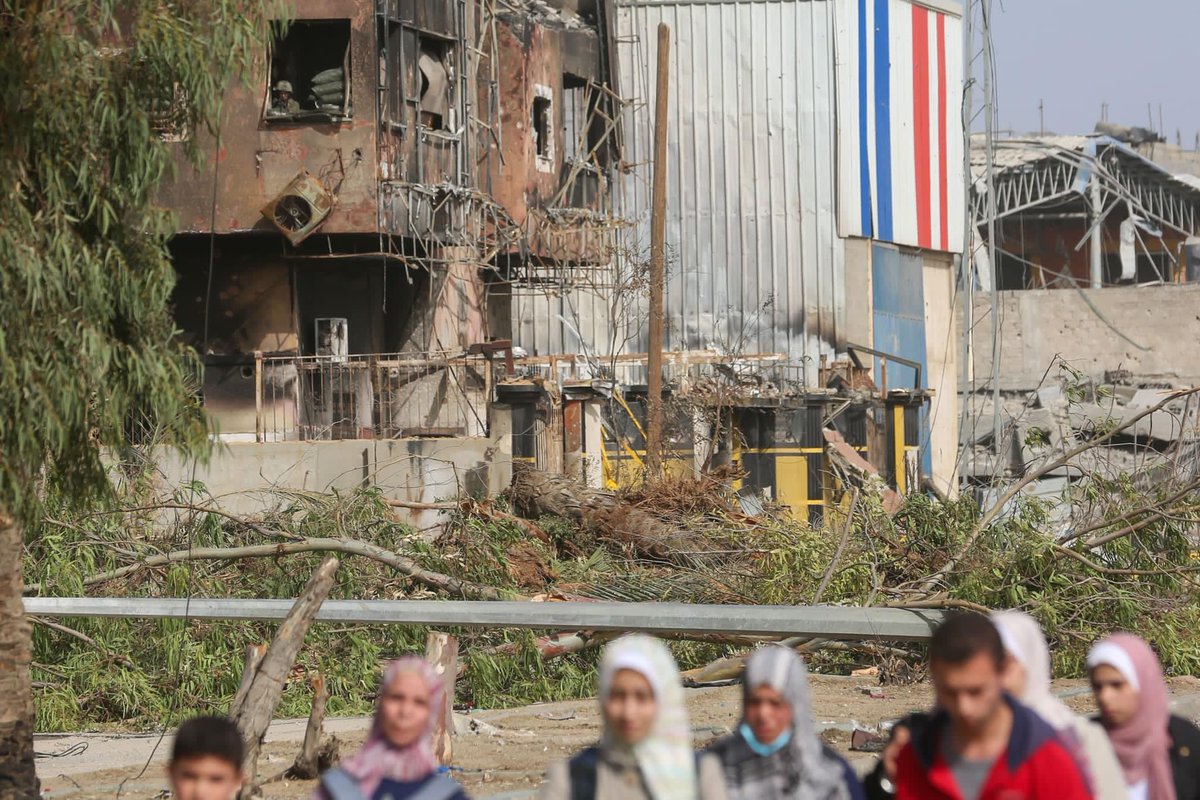 Israeli soldiers pass by displaced individuals from the northern #Gaza Strip. An Israeli soldier monitors Palestinians as they evacuate southward from a window of a destroyed house.