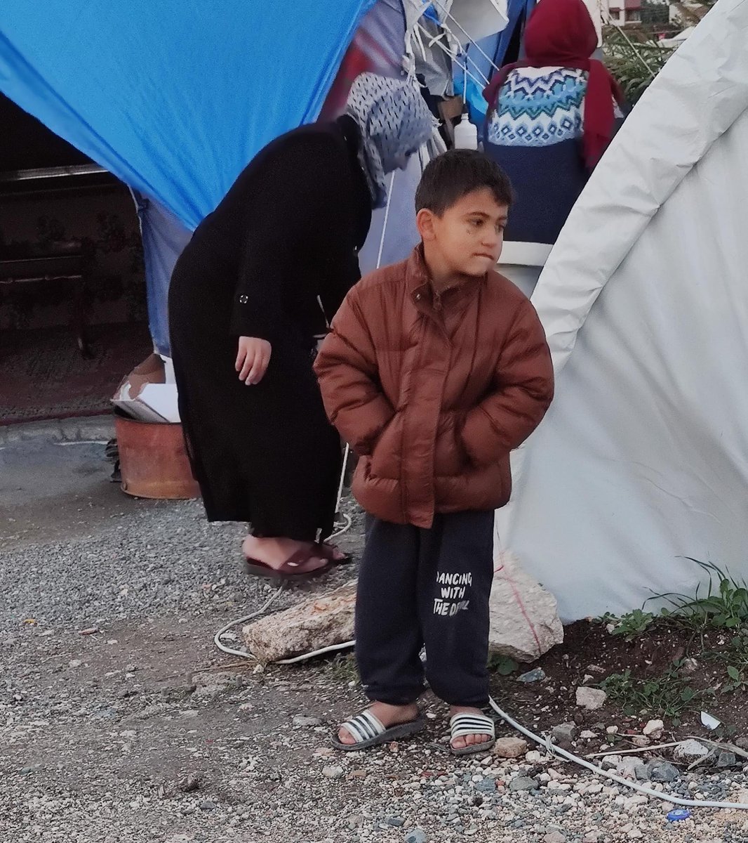dunyazade_'s tweet photo. Çadır yerleşkelerinden bir fotoğraf. Bu çocuğun üşüyen duruşuna ayaklarına eksikliği anlatan bakışlarına bakın. Burası rezerv edilen Hatay burası en büyük yıkımın olduğu Hatay burası Atatürk'ün şahsi bazılarının maddi meselesi Hatay. Bu fotoğrafı çıkaracağım. Fotoğraf sergimizde de göstereceğim. Savaş fotoğraflarındaki çocuklara ne kadar benziyor değil mi? Aslında burda da bir savaş var. Türkiye hükümeti ile halkı arasında anlaşılmaz bir unutturma savaşı amansızca devam ediyor...