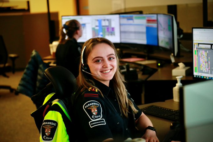 An ambulance communications officer smiles while seated at their desk in the command centre.