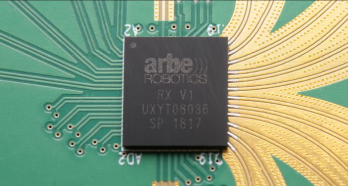 An Arbe RX V1 chip with solder mask covered tracks with sharp angles coming into the chip on the left, and solder mask removed, rounded traces coming out on the right side.