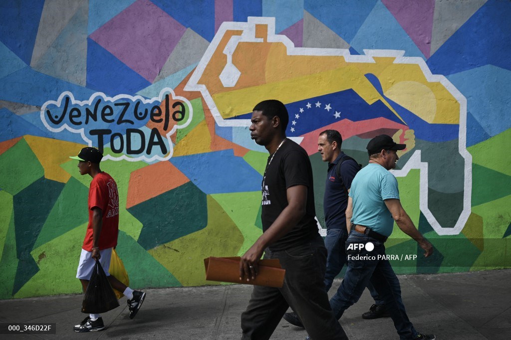 #Venezuela People walk by a mural campaigning for a referendum on December 3 to ask Venezuelans to consider annexing the Guyana-administered region of Essequibo in Caracas. 📷 @federicoparra #AFP