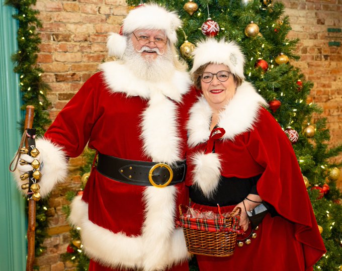 Photo of Santa and Mrs. Claus standing in front of a Christmas Tree.