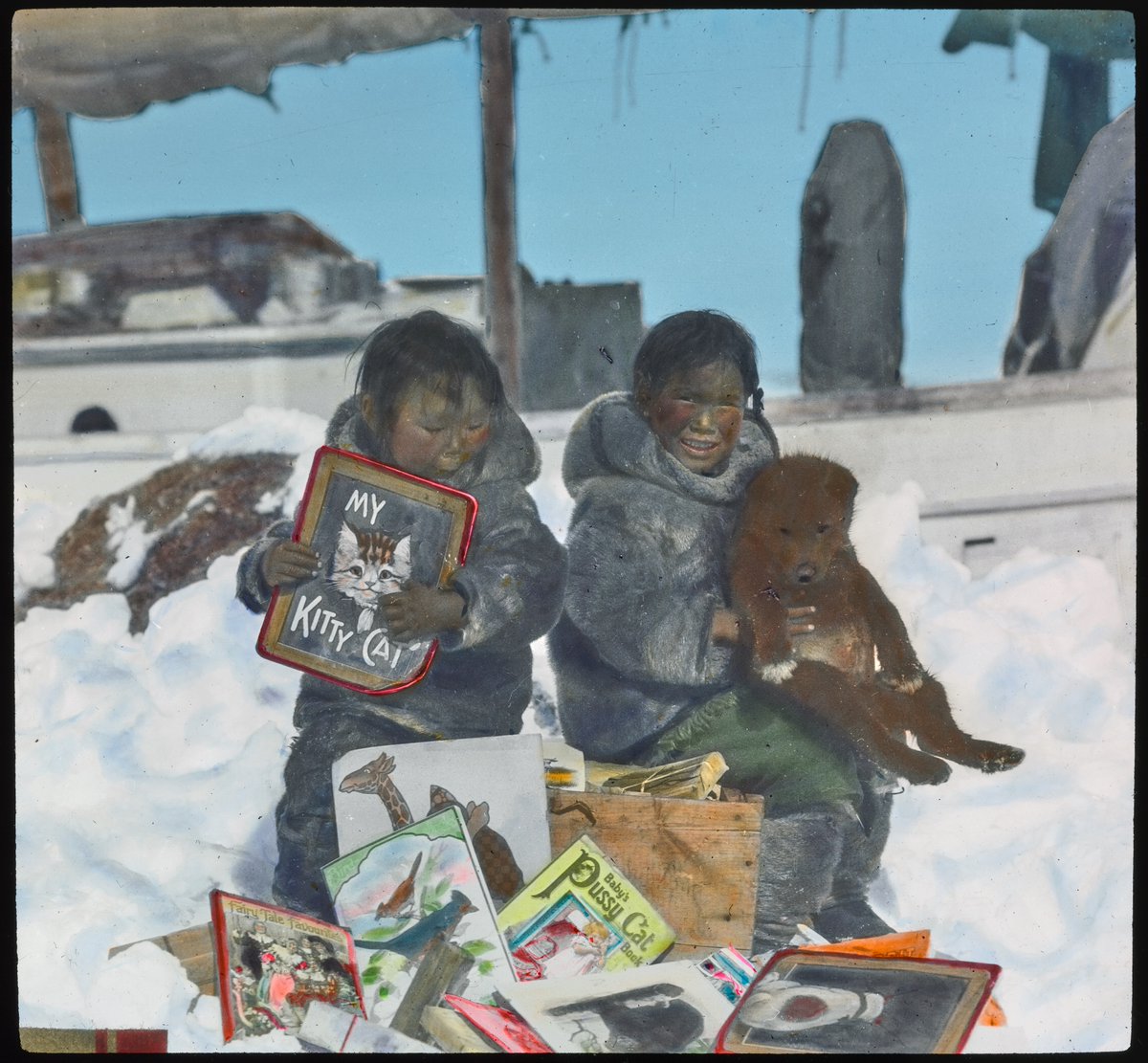 Time to read! Two Inuit children, Sheojuk and Tarkto, sit next to a box of books that were given to them by the crew of the Schooner Bowdoin. The Schooner is in the background.

Photo taken by Donald MacMillan ca. 1921.

#ArchivesHashtagParty #ArchivesGiftExchange