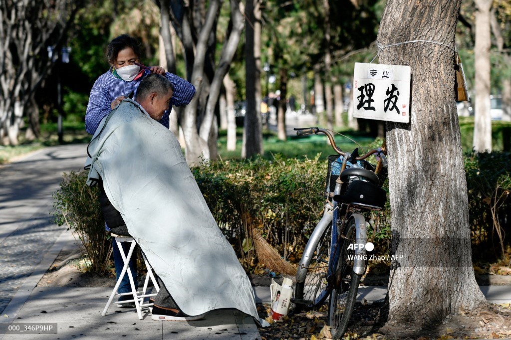 #China A barber cuts a man’s hair along a road in Beijing. 📷 WANG Zhao #AFP