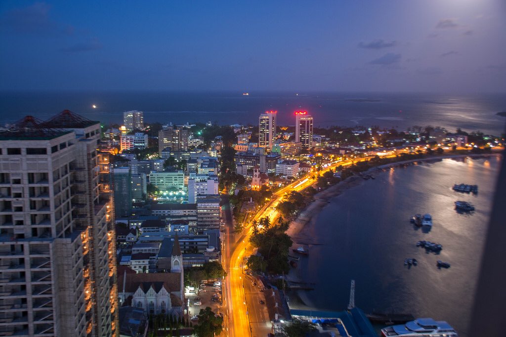 hallaboutafrica's tweet photo. Saturday night and I imagine I'm standing, drink in hand, drinking in the sight of one of our great African cities. Here's Dar es Salaam: a ribbon of golden street arching around moonlight silhouetting anchored ships, while high-rises rise into the Tanzanian evening. https://t.co/TzQnY1UR5L