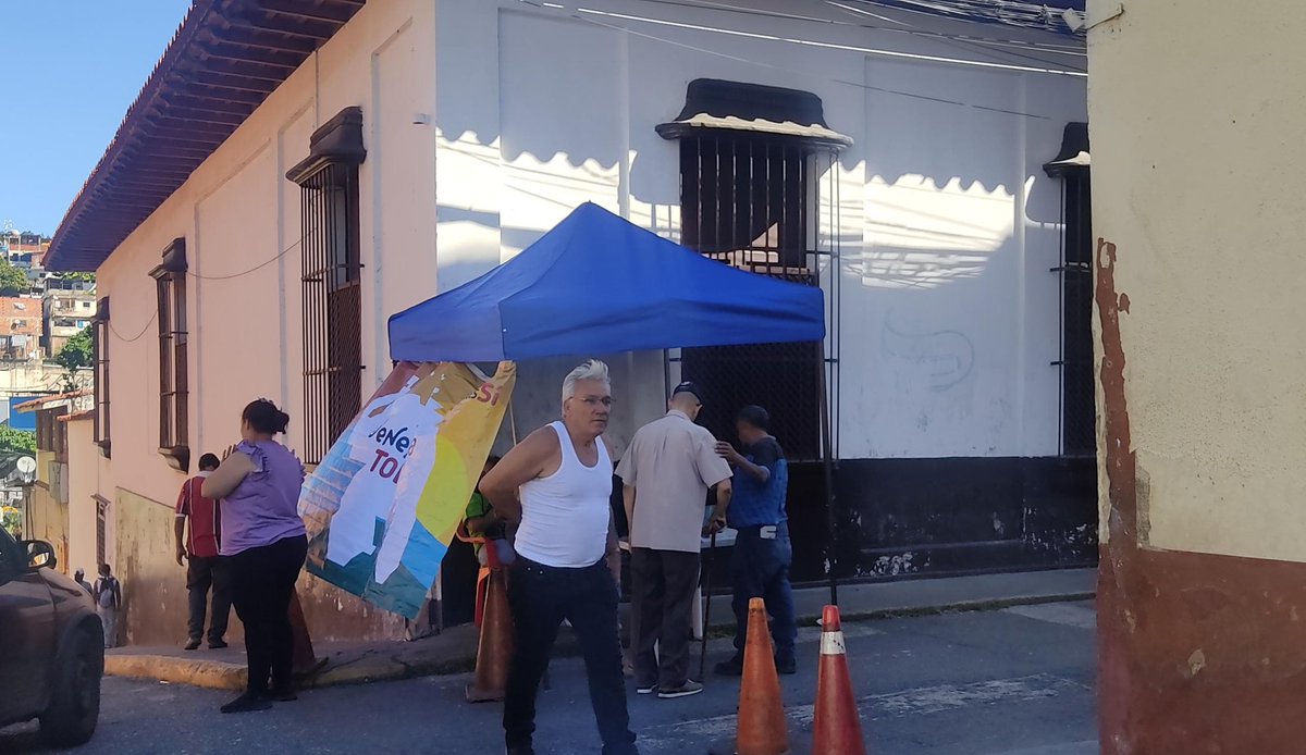 A pocos metros de este centro, los electores son invitados registrarse y escanear el QR del Carnet de la Patria por representantes del chavismo. Vía Kemberly Talero