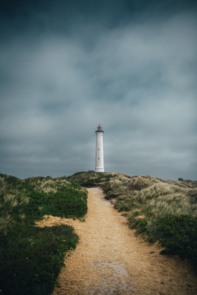 Lyngvig Fyr, a coastal beacon in Denmark, stands tall and proud against the windswept dunes of the North Sea. Its red and white stripes create a picturesque contrast with the azure sky, offering a postcard-worthy scene.

Photo credit 📸: @nicolas_haens_photography_