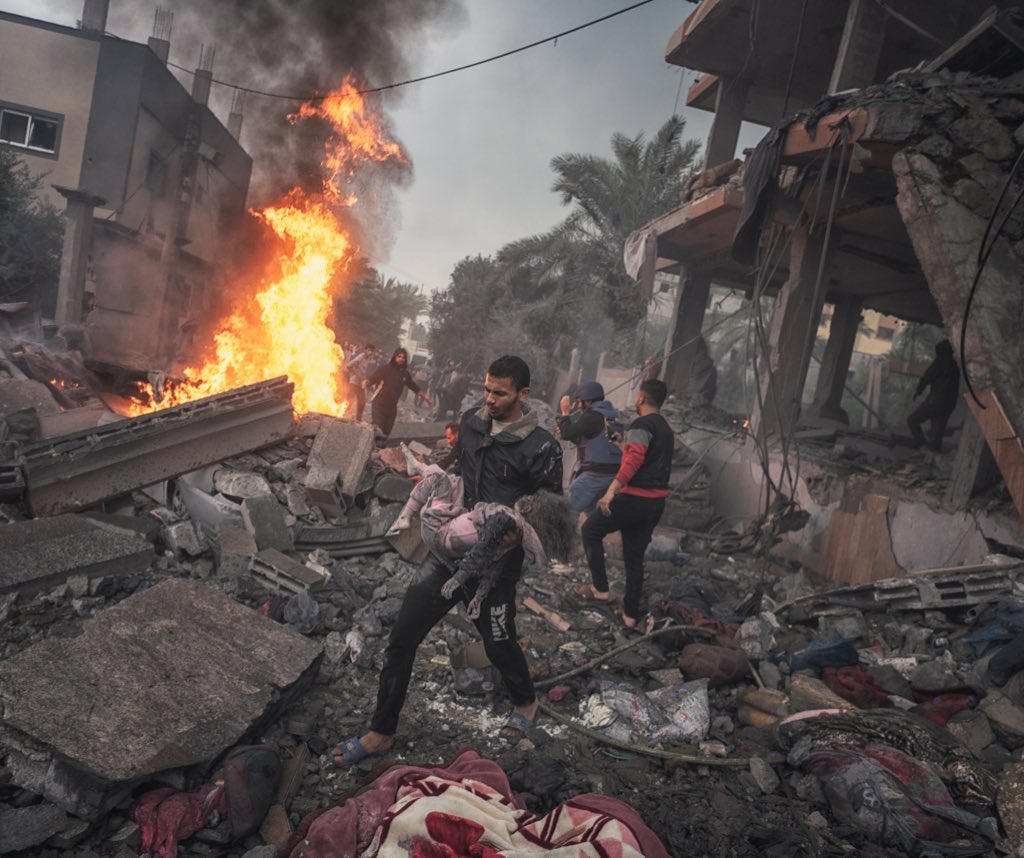 A man is holding a little girl after he extracted her from under the rubble of her destroyed house by the Israeli war planes. This photo have been taken by me from my street today.