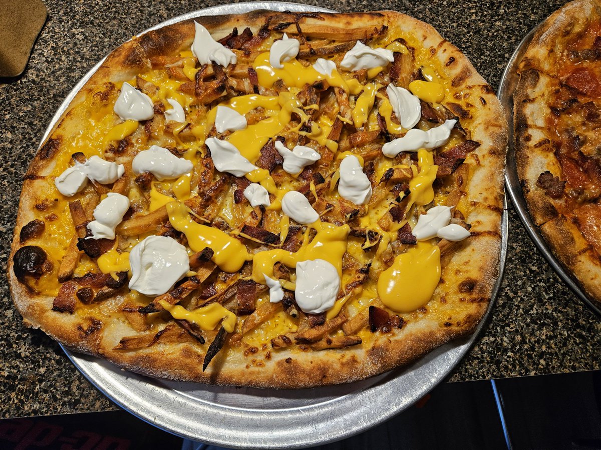 Loaded French fry pizza. Nacho sauce, fries, mozzarella, bacon. Out of the oven add Sour Cream and more nacho cheese.