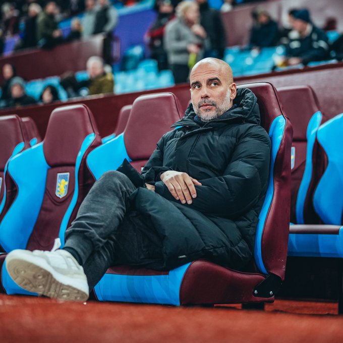 Pep Guardiola takes a seat in the dugout at Villa Park