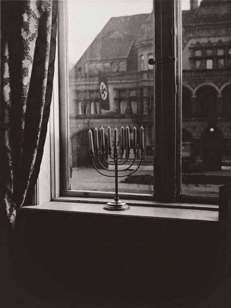Tonight, Jews all over the world will light the first candle of Hanukkah. 
This image of the menorah was taken in 1931 by Rachel Posner at the family’s home in Kiel, Germany, just across from a building decorated with a Nazi flag.
On the back of the photo Rachel wrote:
"Death to