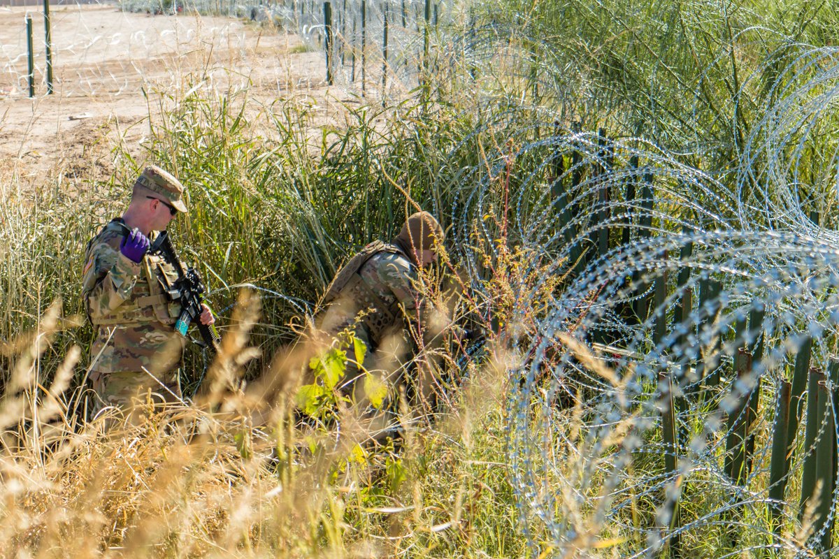 Texas National Guard Soldiers repair a barrier while blocking a group of illegal border crossers. The Guard continues to emplace wire and other barriers to stop illegal border crossings.