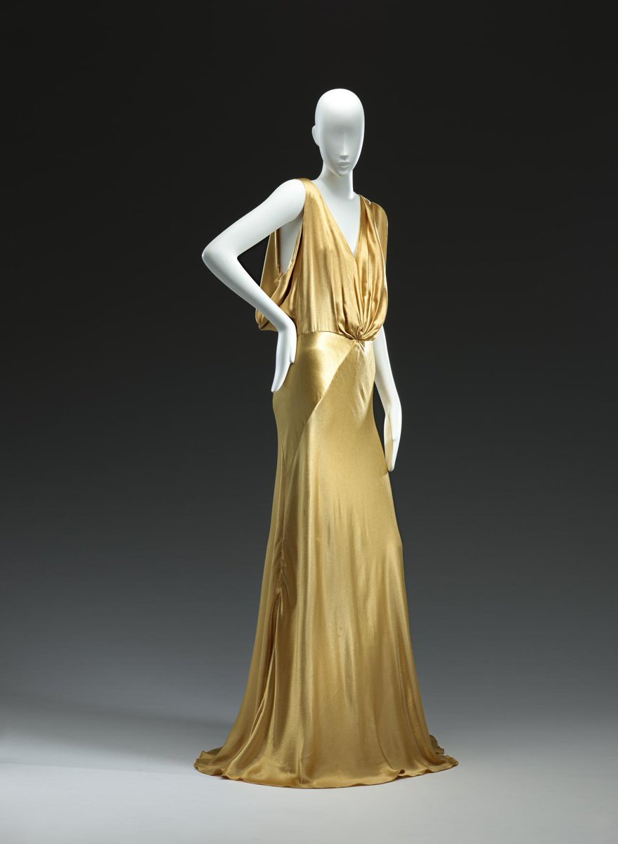 For Day 11 of the #advent party, a golden column of satin, the shift and flicker of shining cloth like a leaping candle flame. The #biascut skirt and deep drape at the neck was designed by Maggy Rouff c1935 @NGVMelbourne #fashionhistory