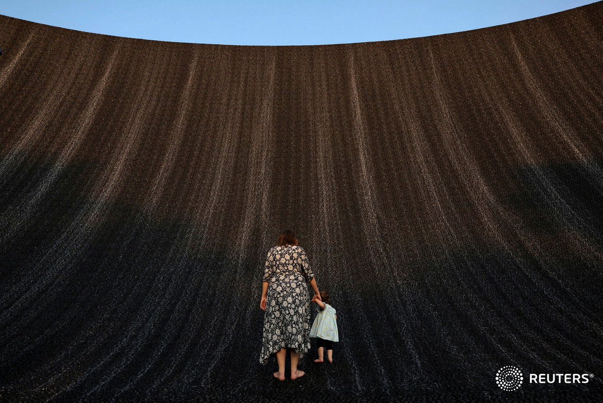 A woman holds an infant's hand as they both enjoy the Expo Waterfall in the Green Zone during the United Nations Climate Change Conference #COP28, in Dubai. — <a href="/Reuters/">Reuters</a>