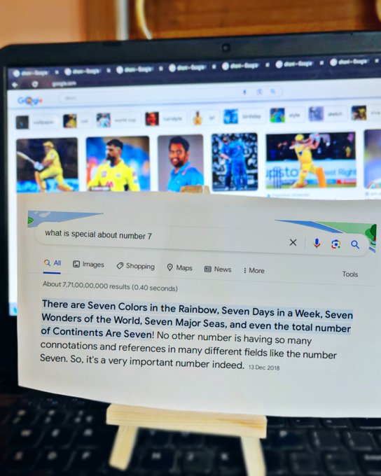 An image with a laptop in the background with seven tabs open on Google Chrome, with 'dhoni' being searched on all of them The currently open tab has the images tab open with multiple images of Indian cricketer M.S Dhoni In the foreground, we have a paper printout of the search query 'what is special about number 7'