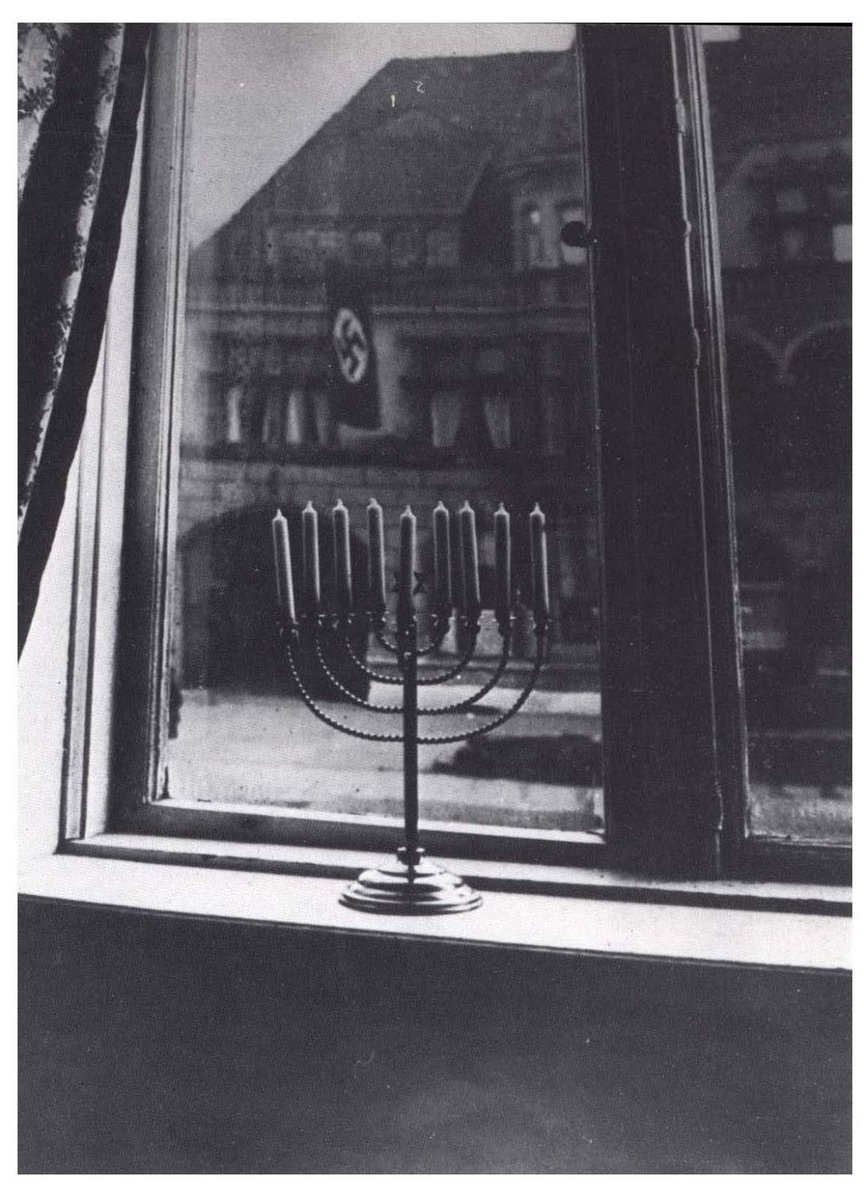 Defying the Nazi flag hanging from the government building across the street, Rachel Posner – wife of Dr. Akiva Posner, the rabbi of Kiel, Germany – took this photograph through her window as her family prepared to light the 8th candle on their Chanukiah.