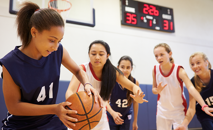 Several youths playing basketball in a gymnasium.