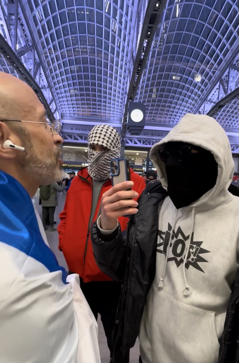 ElishaWiesel's tweet image. Penn Station. Threw an Israeli flag around myself when I saw a crowd of angry Hamas supporters flood the area.  They are cowardly and hide behind their masks. NYPD insisted I remove the flag as the situation was getting dangerous.  Would not let me counterprotest.