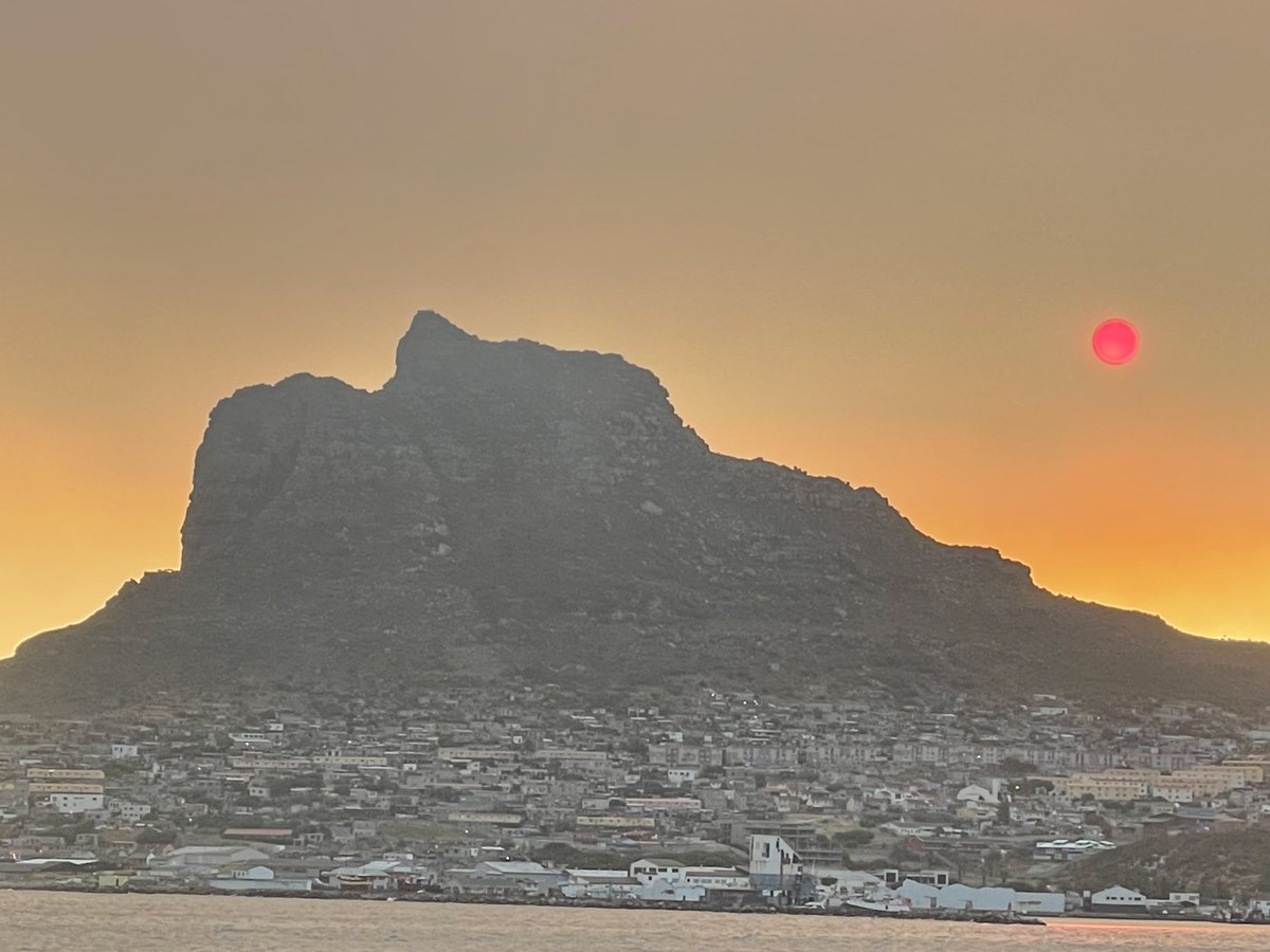 A fire in Simonstown makes a red sun in Hout Bay.